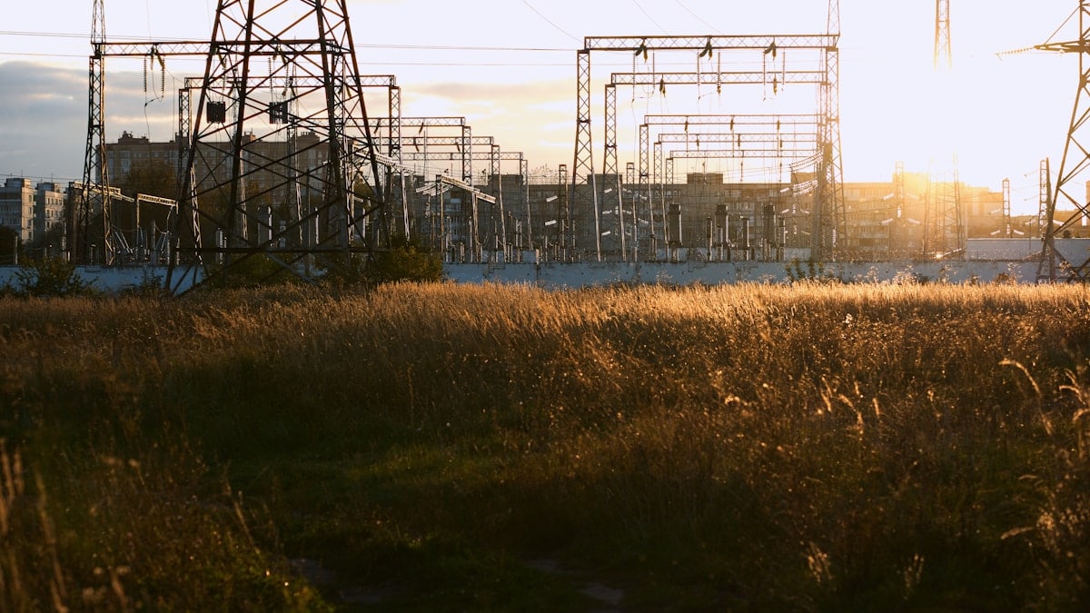 Power station with tall towers and dry grass at sunset